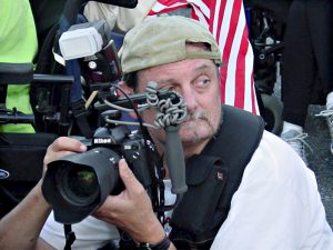 Tom in action holding his camera wearing a backwards cap