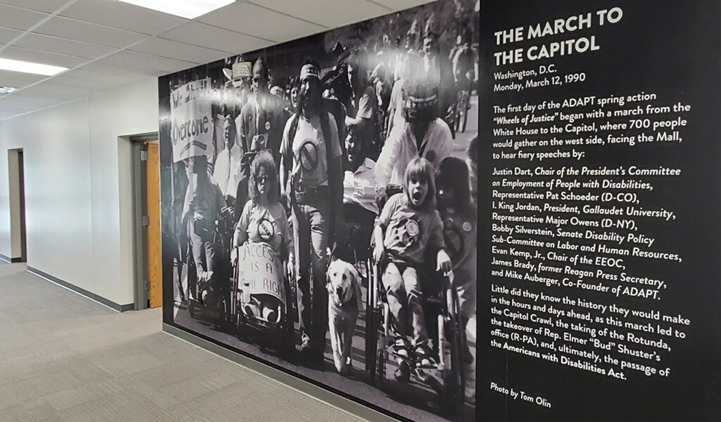 Hallway with Tom Olin's work - a large black and white photo of people protesting"