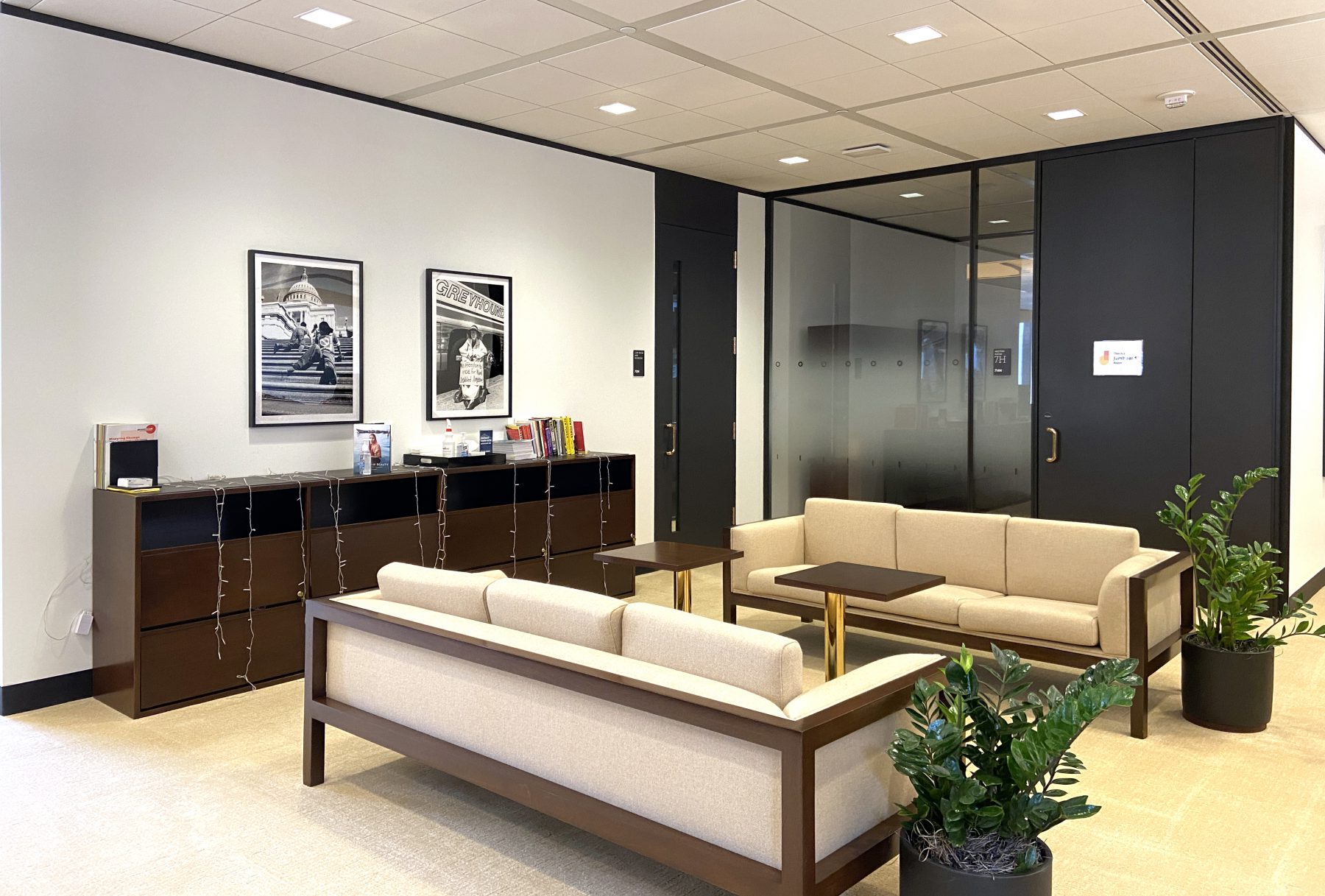 Office lobby with beige couches and black and white photos of Tom Olin photos on the wall