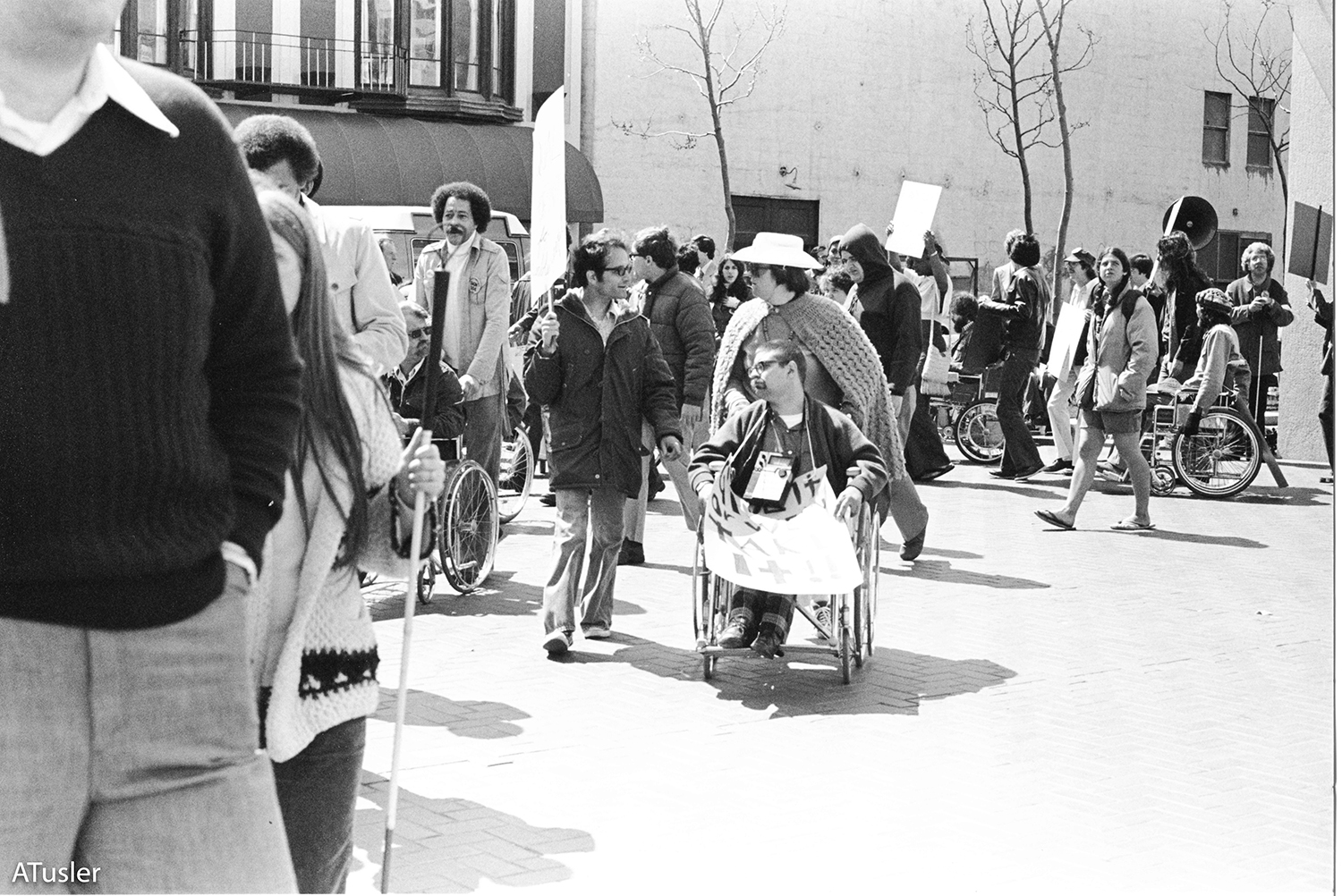 Black and white photo of a line of picketes walking and rolling with signs in hand