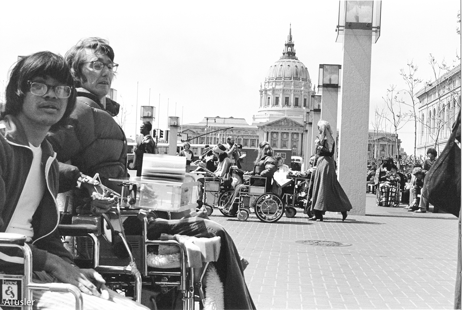 Black and white photo of crowd in front of a building with rotunda, many of the people are wheelchair users.