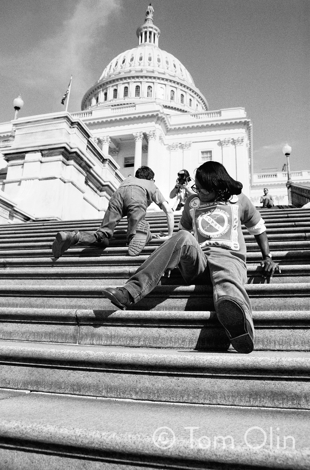 Black and white photo of people crawling up the steps of the U.S. Capitol building in Washington, DC